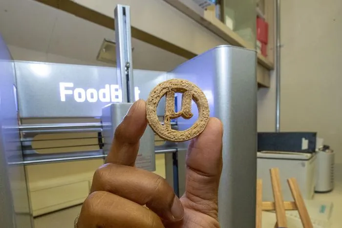 Biscoito de tom claro produzido por impressão 3D de pasta sobre bancada de laboratório