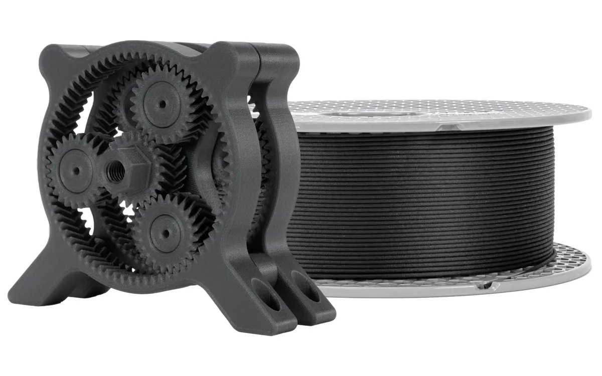 Carretel de filamento Prusament PA11 com fibra de carbono, preto, ao lado de uma caixa de engrenagens planetárias impressa com o mesmo material