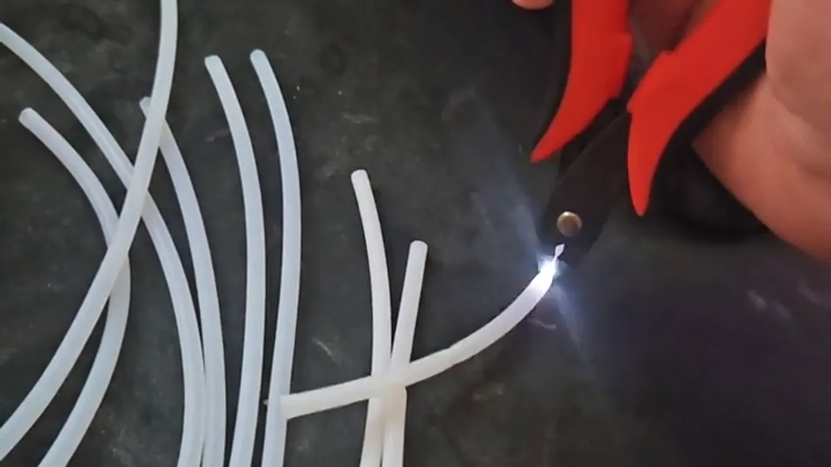 Faísca branca no exato momento em que um alicate corta um tubo de PTFE sobre a bancada