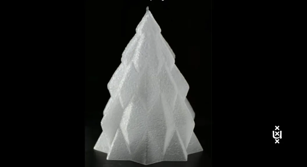 Pequena árvore de Natal translúcida feita de gelo, impressa em 3D camada por camada, sobre uma base metálica dentro de uma câmara