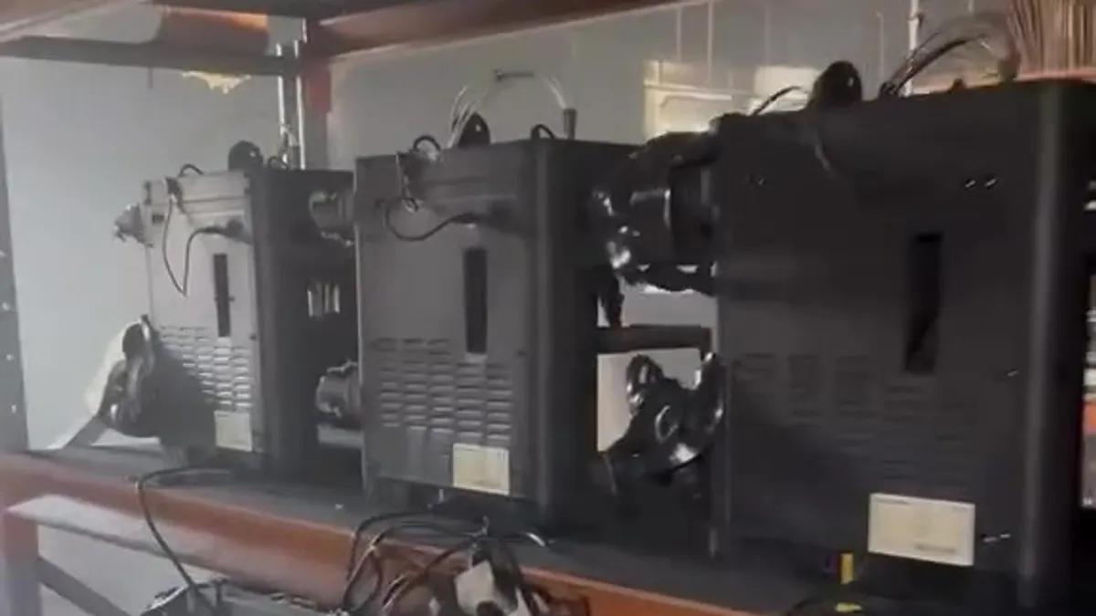Fileira de impressoras 3D derretidas e cobertas de fuligem sobre as prateleiras do galpão incendiado no Paraná