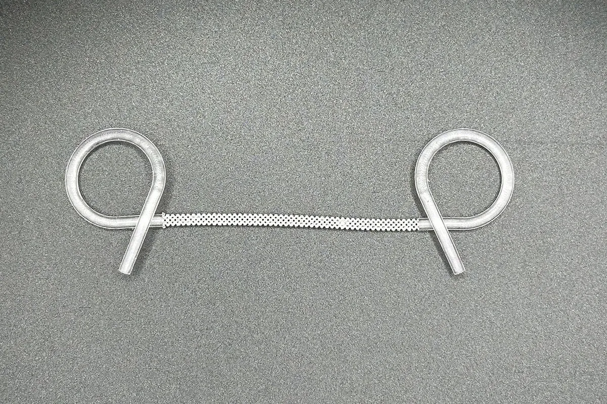 O stent BRIDGE impresso em 3D visto de cima: as duas pontas enroladas em espiral e o trecho central vazado em malha, sobre fundo cinza